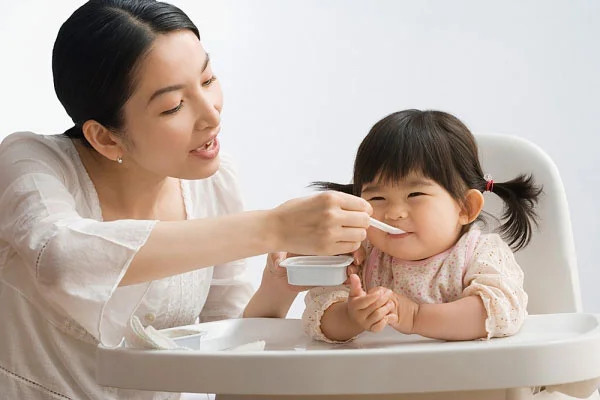 Bé hào hứng ngồi trên ghế ăn dặm chuẩn bị cho bữa ăn
