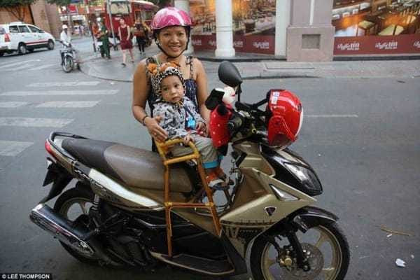 Em bé thoải mái ngồi trong ghế mây an toàn khi đi xe cùng người lớn.
