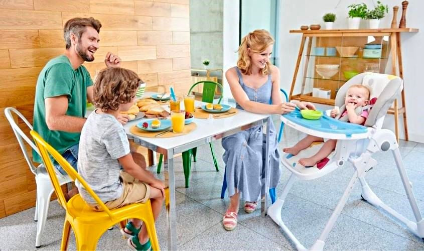 Gia đình quây quần bên bé ngồi ghế ăn dặm cho bé chưa biết ngồi