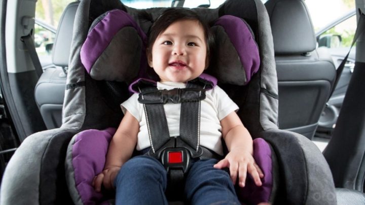 Một bé gái đang nhìn ra ngoài cửa sổ xe ô tô từ ghế trước, thể hiện sự tò mò và dễ bị phân tâm