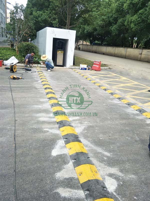 Một đội ngũ chuyên nghiệp đang thi công lắp đặt gờ giảm tốc cao su trên đường giao thông