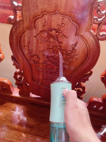 Người phụ nữ đang sử dụng tăm nước để lau ghế gỗ ngày Tết với hoa văn chạm trổ