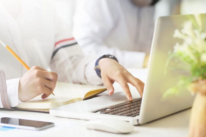 Người phụ nữ làm việc đầy nhiệt huyết với máy tính và sổ ghi chép